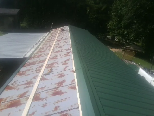 Old rusted panels beside newly installed green metal roofing — Wind Damage Roof Repair by Roofing Brothers in West Jefferson