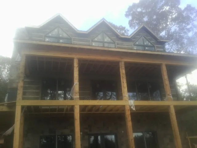 Dormers and porch framing on a large log home under construction — Roof Coating work by our crew in West Jefferson