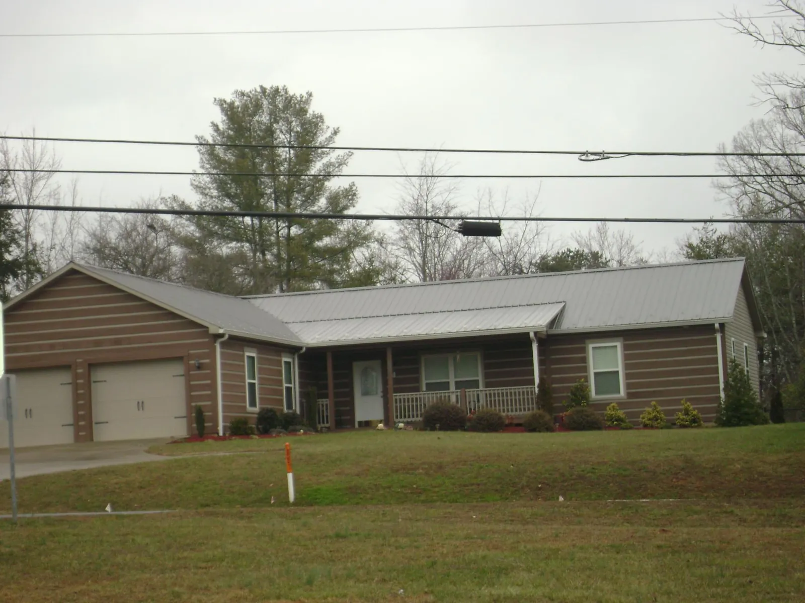 Gray metal roof on a log sided ranch home with a front porch in West Jefferson